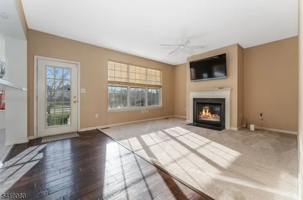 a view of an empty room with wooden floor fireplace and a window