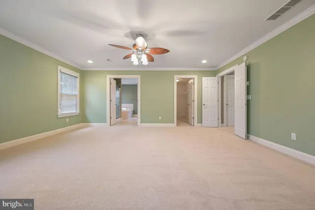 an empty room with a chandelier fan and windows
