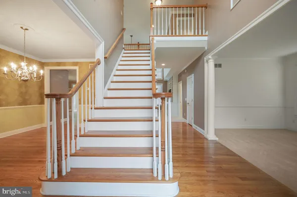 a view of staircase with wooden floor and a chandelier