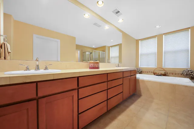 a bathroom with a tub double vanity sink and mirror