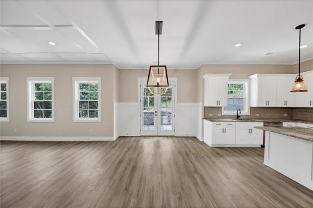 an empty room with wooden floor fireplace cabinet and windows