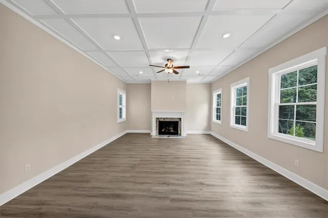 a view of an empty room with kitchen and window