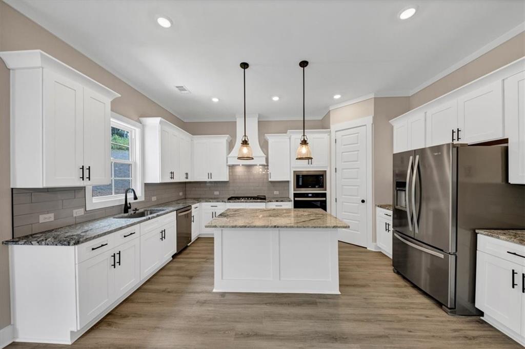 388 Oxford Road Ball Ground, GA 30107 - Photo 9 of 55 a large kitchen with stainless steel appliances kitchen island granite countertop a stove a refrigerator a sink and dishwasher with wooden floor