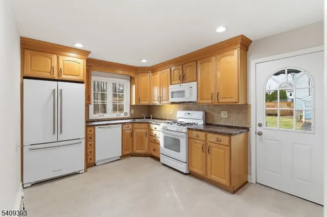 a kitchen with stainless steel appliances granite countertop a refrigerator a stove and a sink with large window