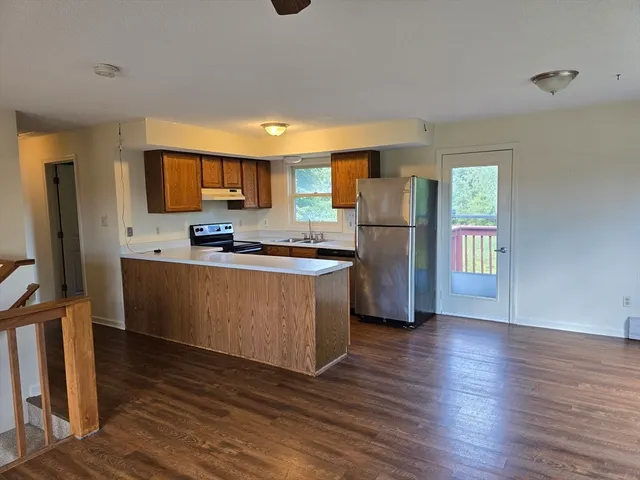 a kitchen with wooden floors stainless steel appliances a sink and a refrigerator