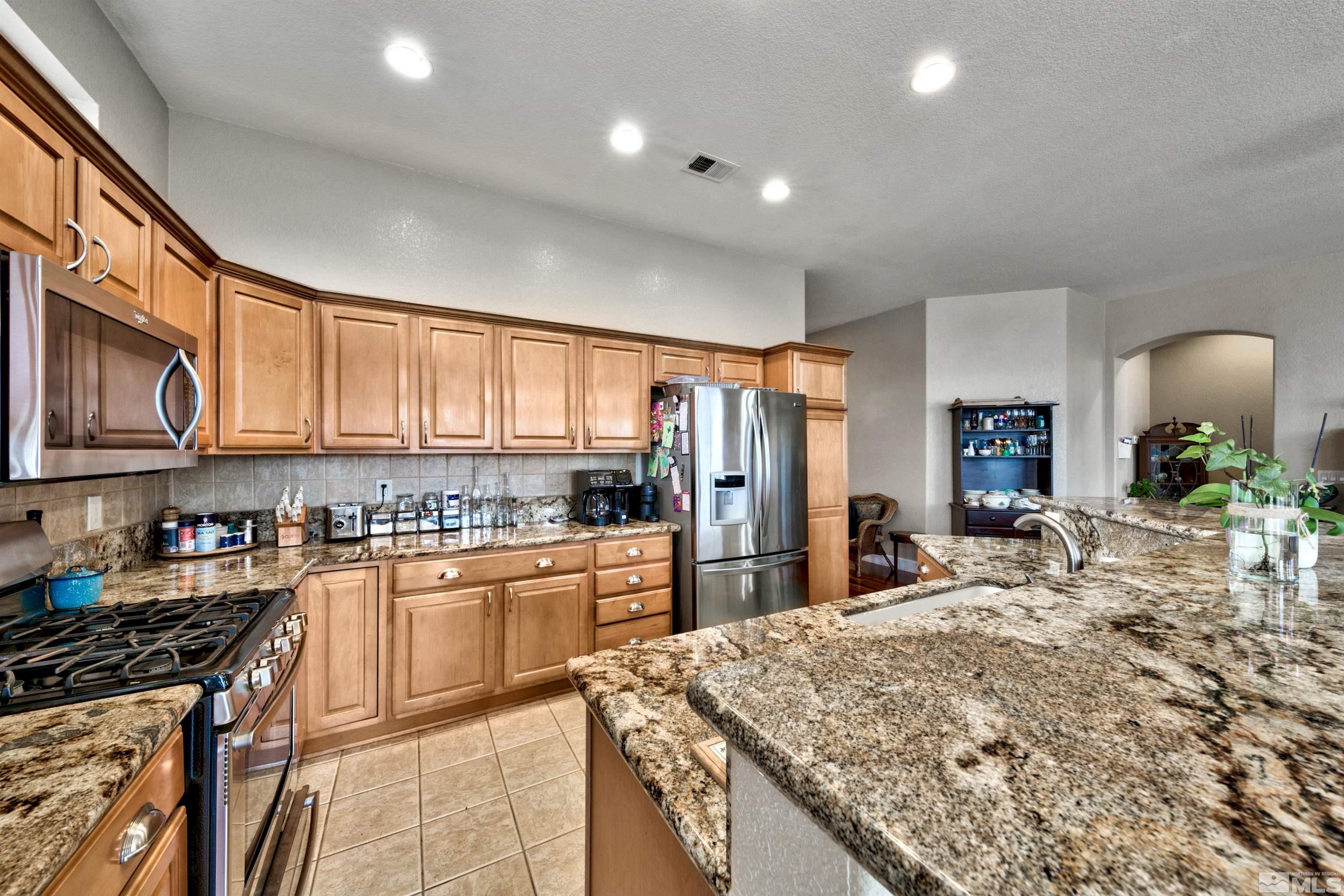 2831 Longridge Drive Carson City, NV 89706 - Photo 16 of 27 a kitchen with stainless steel appliances granite countertop sink stove refrigerator and cabinets