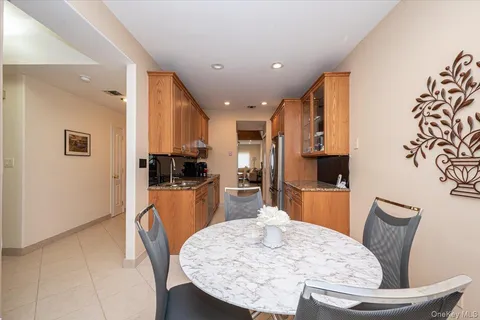 a kitchen with stainless steel appliances kitchen island granite countertop a refrigerator a stove a sink a dining table and chairs with wooden floor