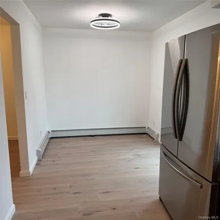 a view of a refrigerator in kitchen and an empty room
