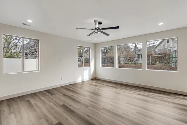 a view of empty room with wooden floor and fan
