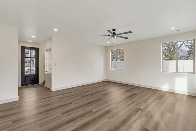 a view of an empty room with a window and wooden floor