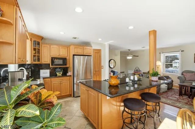 a kitchen with stainless steel appliances granite countertop a refrigerator a stove and a sink with wooden floor