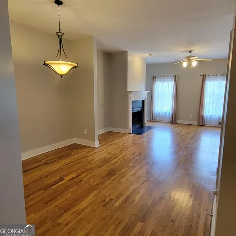 an empty room with wooden floor chandelier fan and windows