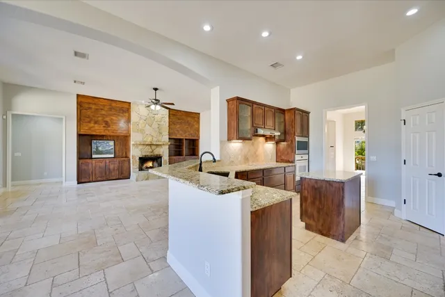 a kitchen with stainless steel appliances granite countertop a stove top oven a sink and a refrigerator
