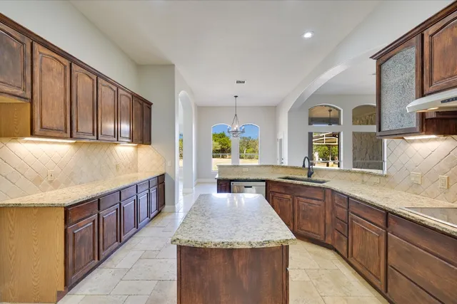 a large kitchen with stainless steel appliances granite countertop a sink and cabinets