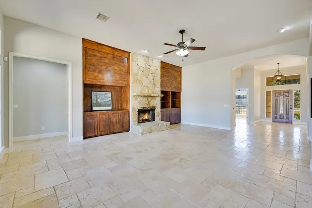 an empty room with chandelier fan and windows
