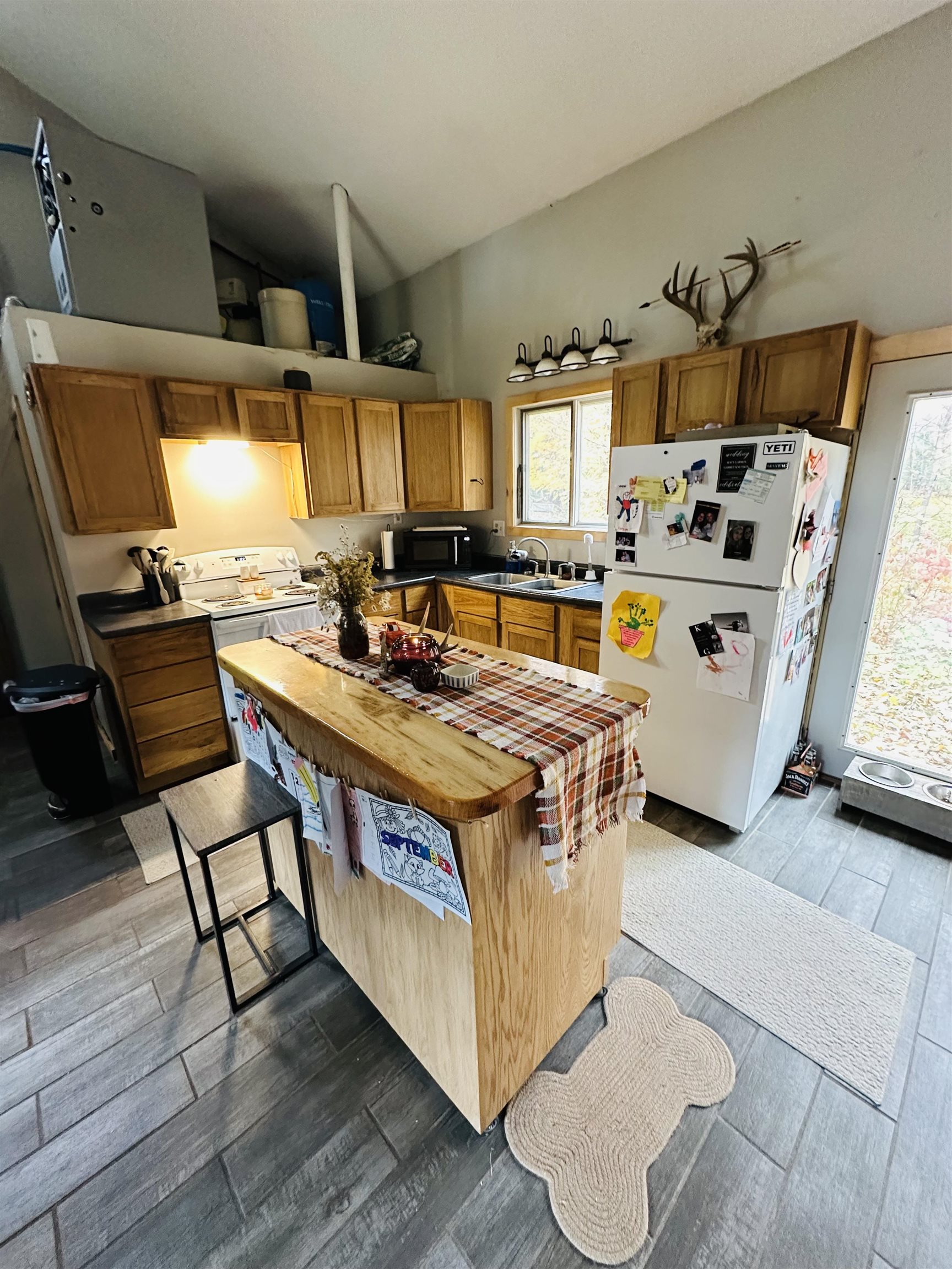 6955 Kolling Road Iron River, WI 54847 - Photo 2 of 22 Kitchen featuring freestanding refrigerator, healthy amount of natural light, lofted ceiling, dark wood-style flooring, and butcher block countertops