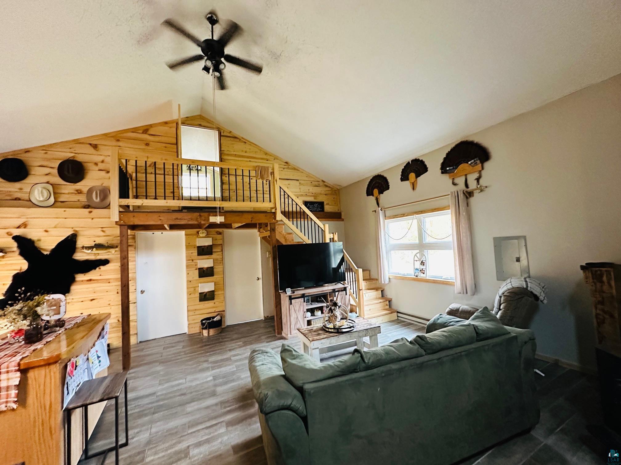 6955 Kolling Road Iron River, WI 54847 - Photo 3 of 22 Living room with wood walls, stairs, ceiling fan, wood finished floors, and electric panel