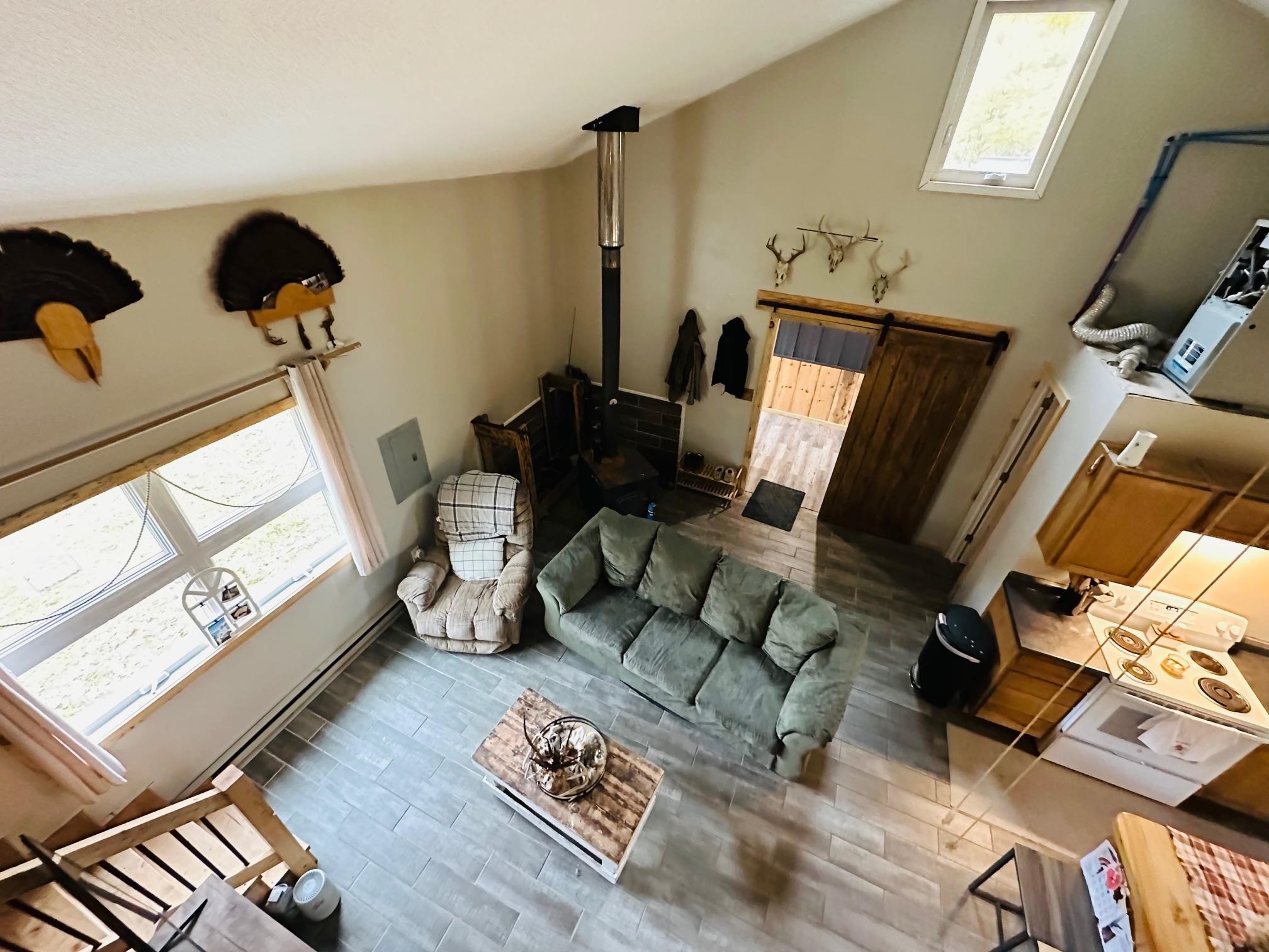 6955 Kolling Road Iron River, WI 54847 - Photo 4 of 22 Living room featuring wood finished floors, a wood stove, and vaulted ceiling
