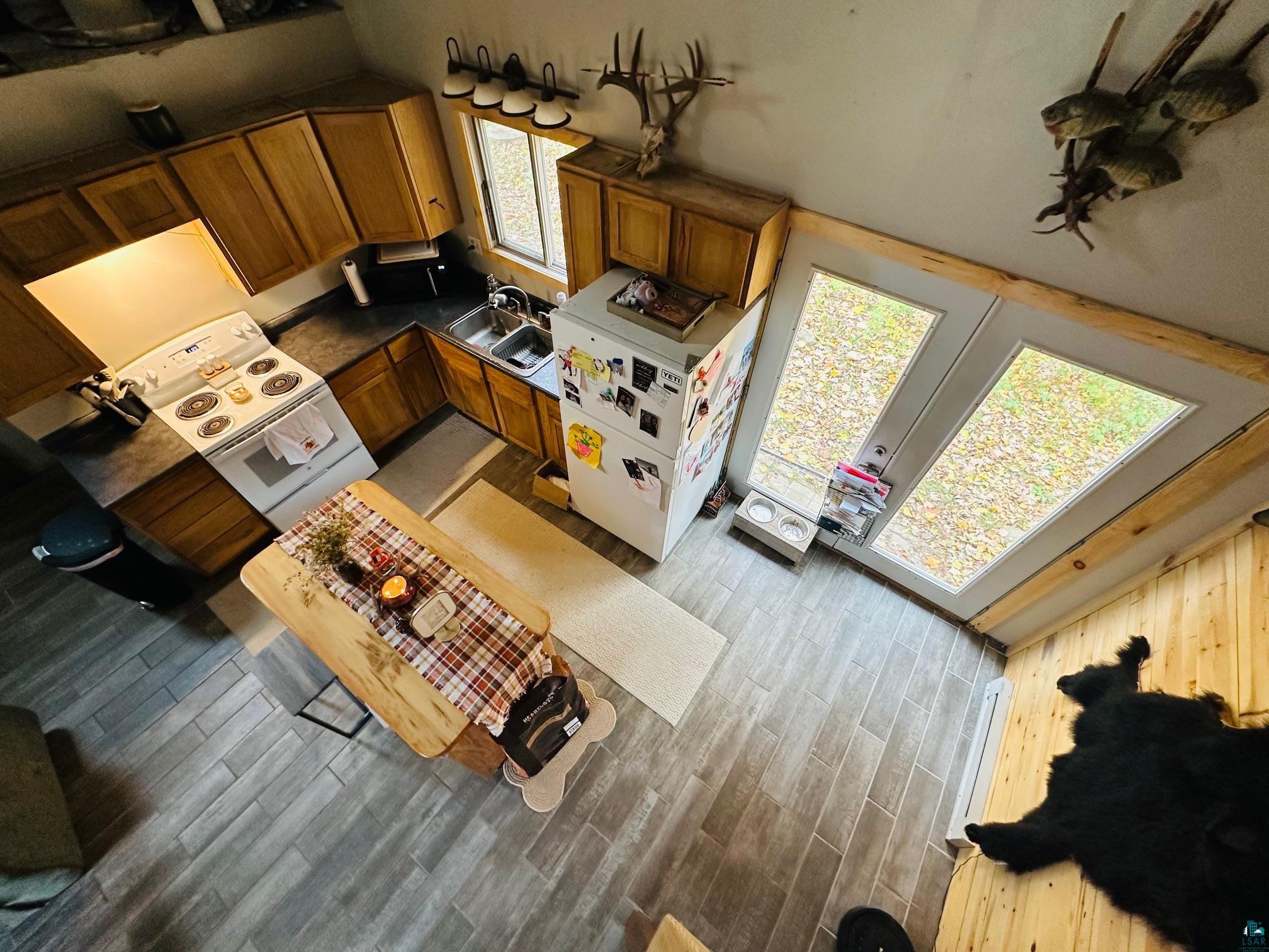 6955 Kolling Road Iron River, WI 54847 - Photo 5 of 22 Kitchen featuring white electric range, dark countertops, brown cabinetry, a towering ceiling, and wood finished floors