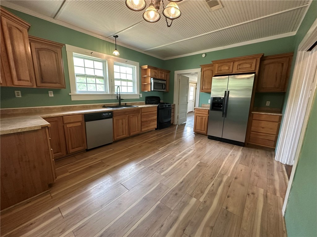 131 Dell Street Portland, TX 78374 - Photo 14 of 40 a large kitchen with stainless steel appliances granite countertop a refrigerator a sink dishwasher a stove and a dining table with wooden floor