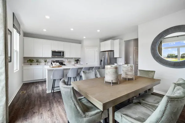 a kitchen with a dining table chairs and refrigerator