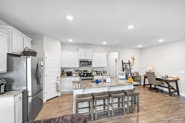 a kitchen with stainless steel appliances a stove a refrigerator a sink dishwasher and a dining table with wooden floor