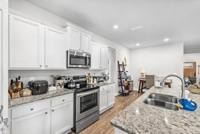 a kitchen with granite countertop a stove sink microwave and cabinets