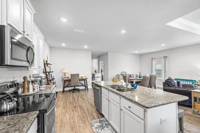 a kitchen with granite countertop a sink stainless steel appliances and cabinets