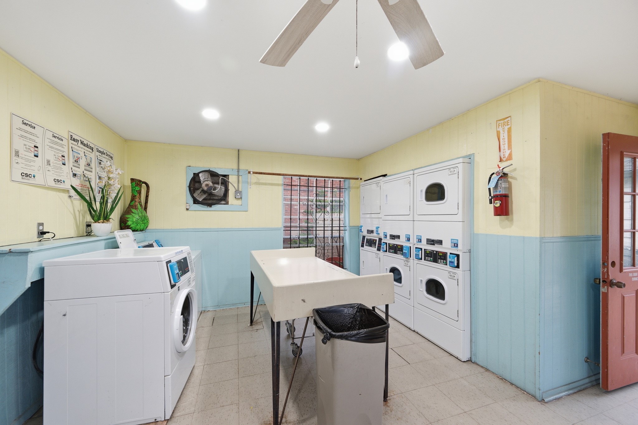 11550 Chimney Rock Road, Unit 133 Houston, TX 77035 - Photo 32 of 40 Spacious laundry room equipped with multiple washers and dryers, featuring ample folding space and a ceiling fan for comfort.