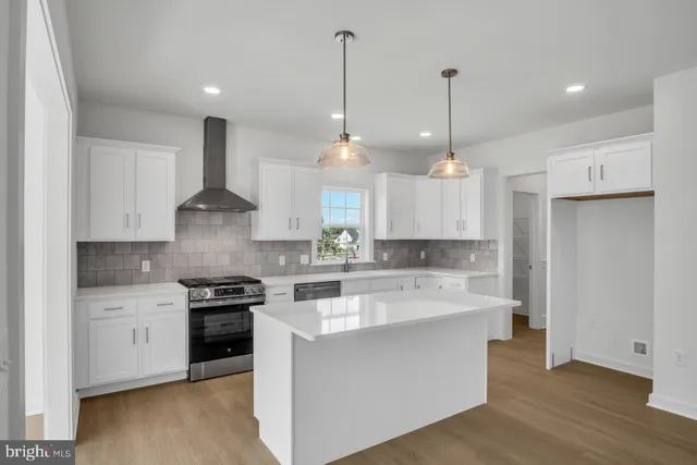 a large kitchen with stainless steel appliances kitchen island granite countertop a stove a sink a center island and a wooden floor