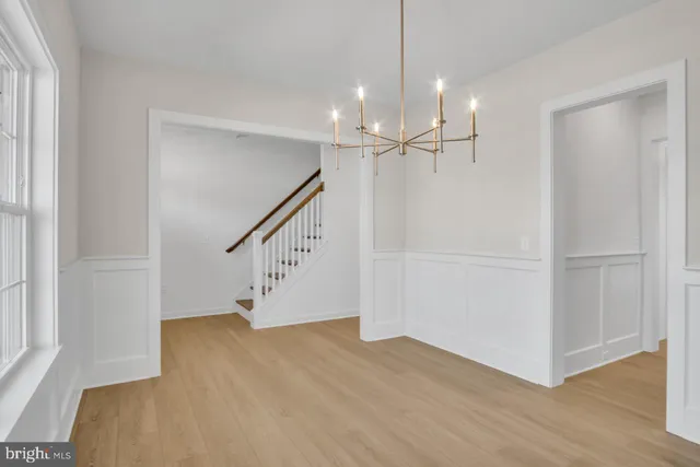 a view of an empty room with wooden floor and stairs