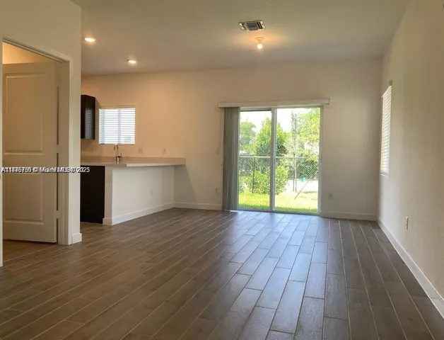 a view of a kitchen with a fridge and wooden floor