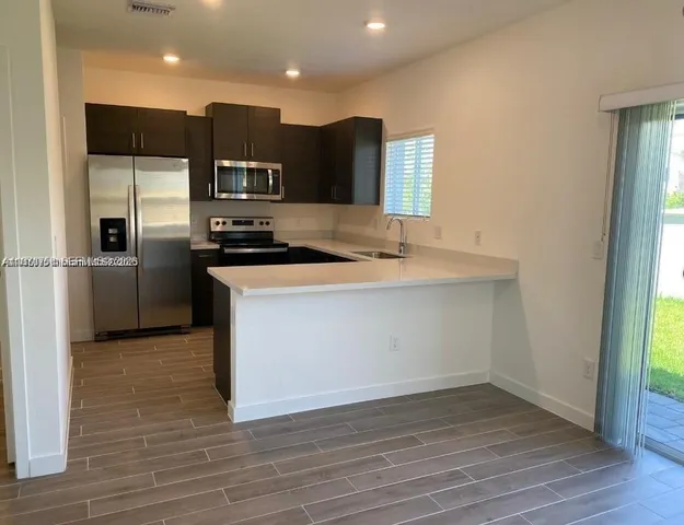 a kitchen with stainless steel appliances granite countertop a sink a stove and a refrigerator