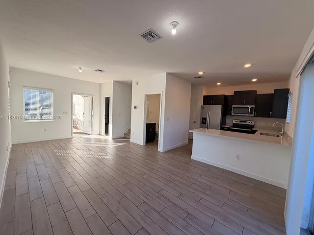 a view of kitchen with refrigerator stove and wooden floor