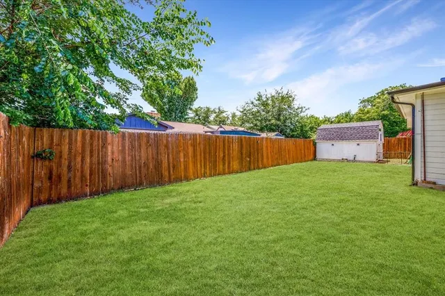 a view of a backyard with large trees and wooden fence