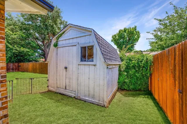 a view of backyard with small cabin and wooden fence