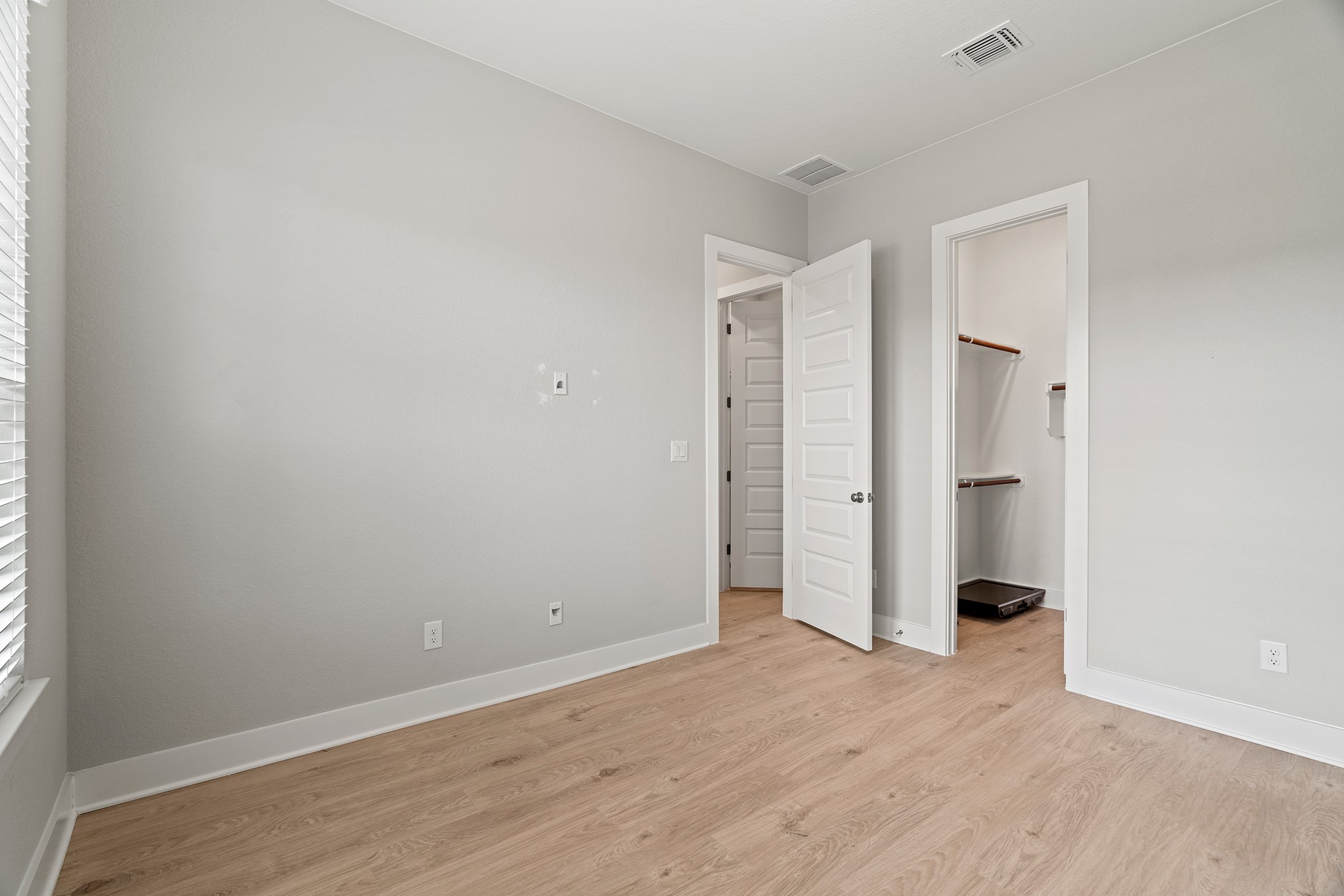 2112 Tobiano Trace Georgetown, TX 78633 - Photo 23 of 40 Unfurnished bedroom featuring light wood-type flooring, multiple windows, and a spacious closet