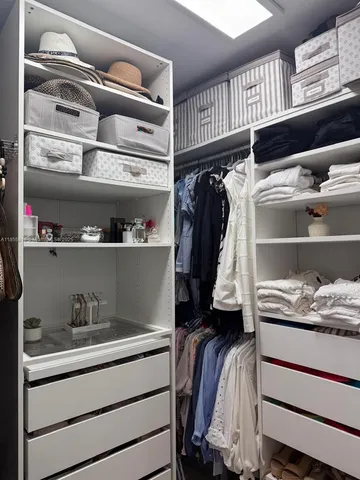 a view of walk in closet with clothes and shoes