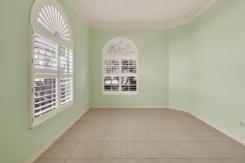 an empty room with a chandelier fan and windows