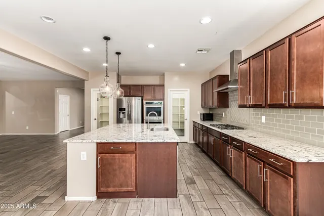 a large kitchen with stainless steel appliances kitchen island granite countertop wooden cabinets a sink and dishwasher