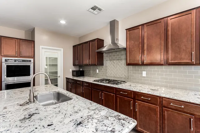 a kitchen with stainless steel appliances granite countertop a sink stove and cabinets