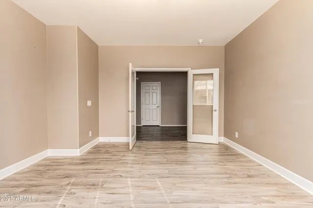 a view of an empty room with wooden floor and kitchen