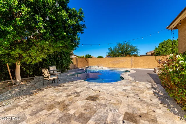a view of a backyard with table and chairs potted plants and large tree