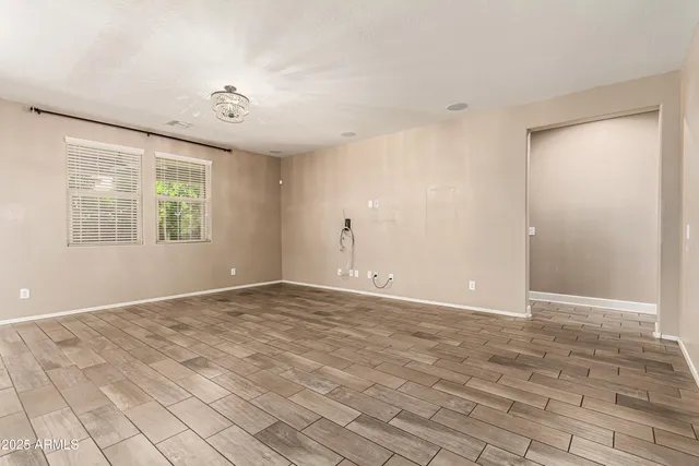 a view of an empty room with window and hardwood floor
