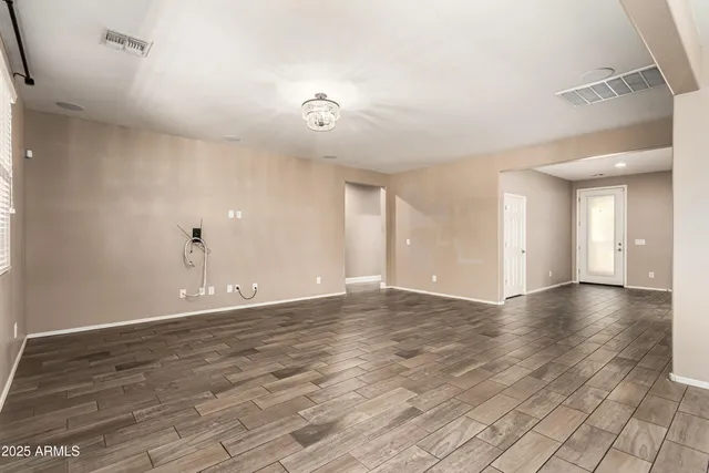 a view of an empty room with window and wooden floor