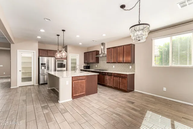 a large kitchen with stainless steel appliances kitchen island granite countertop a stove a sink a refrigerator and a wooden floors