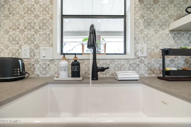 a kitchen with stainless steel appliances granite countertop a refrigerator a sink dishwasher a dining table and chairs with wooden floor