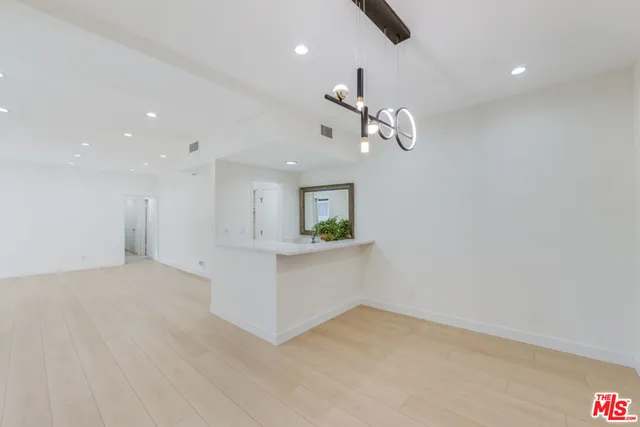 a view of an empty room with kitchen and a window