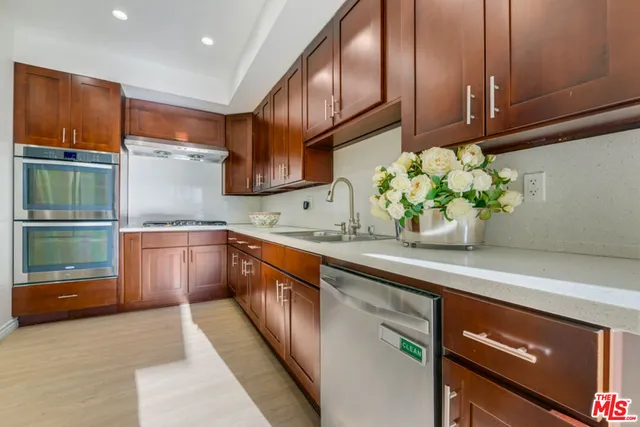 a kitchen with stainless steel appliances granite countertop wooden cabinets a stove top oven a sink and dishwasher