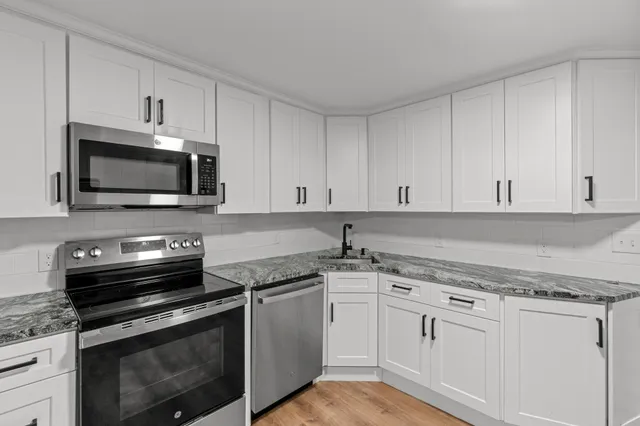 a kitchen with granite countertop white cabinets and stainless steel appliances